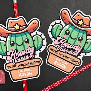 Puede incluir: Dos tarjetas de San Valentín imprimibles con un cactus de dibujos animados que lleva un sombrero de vaquero. El texto de las tarjetas dice "Howdy Valentine You're Looking Sharp!" e incluye el nombre "Austin".