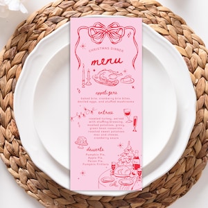 Puede incluir: Una tarjeta de menú de cena de Navidad rosa con ilustraciones rojas. El menú incluye aperitivos, entrantes y postres. La tarjeta está sobre un plato blanco, colocado sobre un mantel individual tejido.