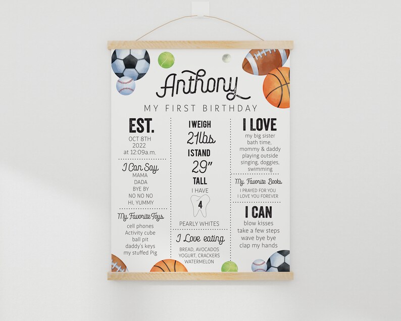 May include: A colorful printable first birthday chart for a boy named Anthony. The chart features a sports theme with illustrations of baseballs, basketballs, soccer balls, and tennis balls. The chart includes information about Anthony's age, weight, height, favorite toys, foods, books, and activities. The text on the chart reads: "Anthony, My First Birthday, Est. Oct 8th 2022 at 12:09 a.m., I Weigh 21 lbs, I Stand 29" Tall, I Have 4 Pearly Whites, I Love My Big Sister, Bath Time, Mommy & Daddy, Playing Outside, Singing, Doggies, Swimming, My Favorite Books: I Prayed For You, I Love You Forever, I Can Blow Kisses, Take A Few Steps, Wave Bye Bye, Clap My Hands, I Can Say: Mama, Dada, Bye Bye, No No No, Hi Yummy, My Favorite Toys: Cell Phones, Activity Cube, Ball Pit, Daddy's Keys, My Stuffed Pig, I Love Eating: Bread, Avocados, Yogurt, Crackers, Watermelon."