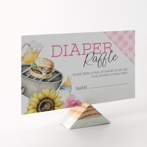May include: A pink and white diaper raffle card with a watercolor illustration of a grill, a hamburger, a beer, a sunflower, and a baby bottle. The text on the card reads "DIAPER Raffle" and "PLEASE BRING A PACK OF DIAPERS IN ANY SIZE TO BE ENTERED TO WIN A PRIZE". There is a blank line for a name.