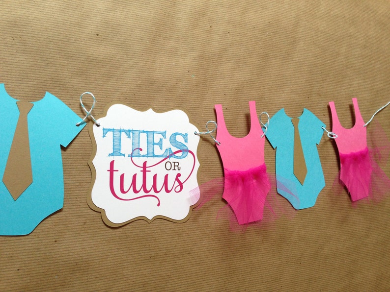 Pode incluir: Uma faixa de revela&ccedil;&atilde;o de g&ecirc;nero com recortes de papel azul e rosa de macac&otilde;es, uma gravata e um tutu. A faixa tamb&eacute;m inclui uma placa que diz "Ties or Tutus".