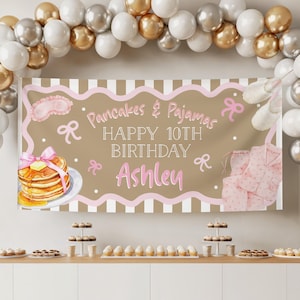 Może przedstawiać: Baner urodzinowy z napisem "Pancakes & Pajamas HAPPY 10TH BIRTHDAY Ashley" w kolorze różowym i białym. Baner zawiera ilustracje naleśników, piżamy, maski do spania i kokardek. Nad nim łuk balonowy, a pod nim desery.
