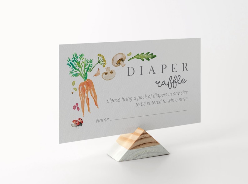 May include: A white card with a watercolor illustration of a carrot, mushrooms, and leaves. The text on the card reads "DIAPER raffle please bring a pack of diapers in any size to be entered to win a prize Name_"