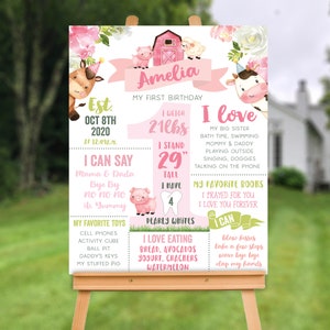 May include: A personalised first birthday milestone sign featuring a pink barn, farm animals, and floral accents. The text includes the name Amelia, birth date 8 Oct 2020, weight 9.5kg, height 74cm, 4 teeth, favourite toys, foods, and activities.