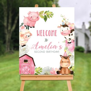 May include: A rectangular welcome sign featuring watercolour illustrations of a pink pig, a white sheep, a black and white cow, and a brown horse, all decorated with pink flowers and a red barn. The text reads: WELCOME to Amelia's SECOND BIRTHDAY!