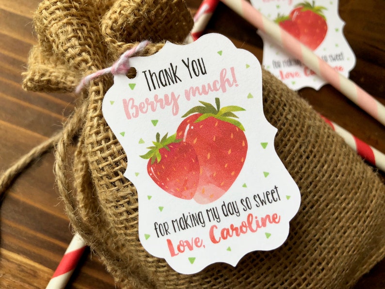May include: A white thank you tag with a pink border and green polka dots. The tag features a drawing of two red strawberries and the text "Thank You Berry much!" and "for making my day so sweet Love, Caroline".