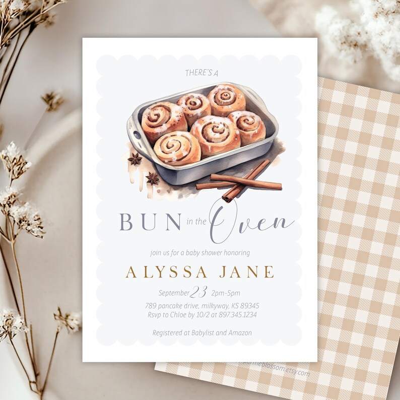 Może przedstawiać: Zaproszenie na baby shower z akwarelową ilustracją bułek cynamonowych w brytfannie. Tekst brzmi "Bun in the Oven" i zawiera imię Alyssa Jane, datę, godzinę i miejsce.