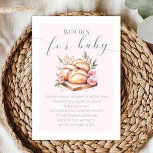 May include: A baby shower sign with the words "BOOKS for baby" in elegant script. The sign features a watercolor illustration of bread rolls, flowers, and greenery. The text below requests a signed storybook instead of a card.