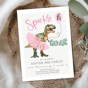 May include: A white invitation card with a watercolor illustration of a dinosaur wearing a pink tutu. The text "Sparkle & Roar" is written in pink and green. The invitation is for a birthday party.