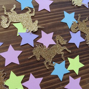 May include: A collection of gold glitter unicorn and star confetti. The stars are in various colors including light blue, light purple, light green, and yellow.