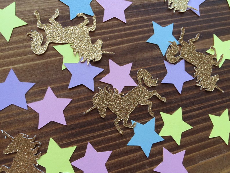 May include: A collection of gold glitter unicorn and star confetti. The stars are in various colors including light blue, light purple, light green, and yellow.