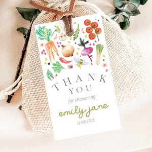 May include: White thank you tag with a watercolor illustration of vegetables, a bee, and flowers. The text reads "Thank You for showering Emily Jane 12.08.2025".