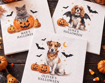Op de afbeelding: Drie vierkante witte papieren servetten met Halloween-illustraties. Eén toont een grijze kat in een pompoen met 'MAX'S HALLOWEEN', één een hond met vleermuisvleugels met 'LUNA'S HALLOWEEN', en één een hond met een bandana met 'OLIVER'S HALLOWEEN'.