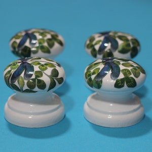 Może przedstawiać: Cztery białe ceramiczne gałki do szafek z wzorem zielonej i niebieskiej ważki.
