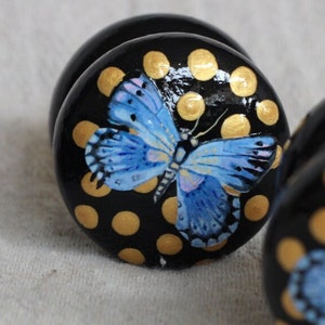 May include: Three black wooden knobs with gold polka dots and blue butterfly designs.