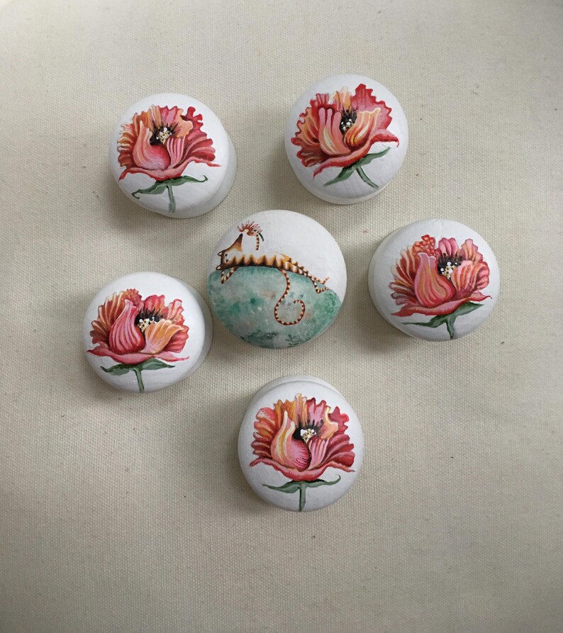 Puede incluir: Seis piedras decorativas redondas blancas. Cinco piedras presentan un dise&ntilde;o floral rojo y rosa. La sexta piedra tiene una criatura parecida a un caballito de mar sobre un fondo turquesa. Las piedras est&aacute;n pintadas a mano.