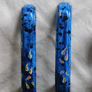 May include: Two blue painted cabinet door pulls with a design of small yellow and orange fish on a blue background.