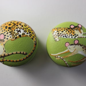 Op de afbeelding: Twee ronde, groen geverfde houten dozen met een luipaardprint. Een doos heeft een luipaard dat ligt, de andere heeft een luipaard dat opgerold is.