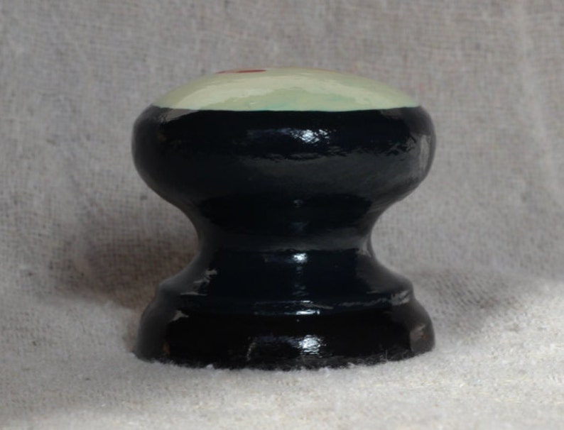 Puede incluir: Un pomo decorativo de madera pintado a mano con una parte superior redondeada. La parte superior es de color verde claro con un peque&ntilde;o acento rojo, y el cuerpo es negro. El pomo tiene una forma cl&aacute;sica torneada, adecuada para muebles o decoraci&oacute;n.