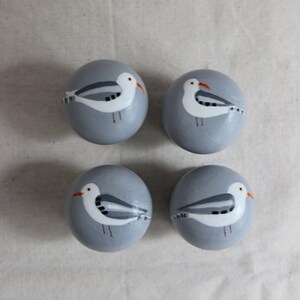 K&ouml;nnte beinhalten: Vier grau bemalte Eier mit wei&szlig;en M&ouml;wenmotiven. Jedes Ei hat eine andere M&ouml;wenpose.