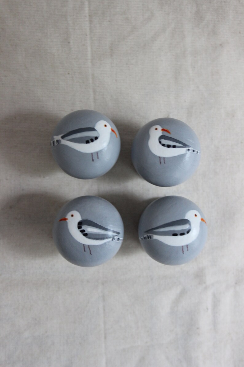 K&ouml;nnte beinhalten: Vier grau bemalte Eier mit wei&szlig;en M&ouml;wenmotiven. Jedes Ei hat eine andere M&ouml;wenpose.