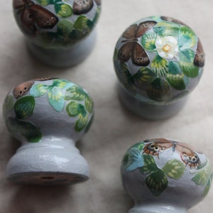 K&ouml;nnte beinhalten: Vier Keramikkn&ouml;pfe mit einer hellblauen Basis und einem wei&szlig;en, gr&uuml;nen und braunen Schmetterlingsdesign.