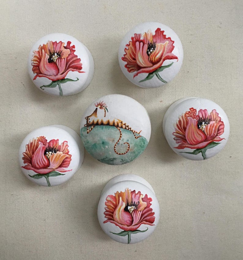 Puede incluir: Seis piedras blancas lisas pintadas a mano. Cinco piedras presentan una vibrante flor roja y rosa con tallos y hojas verdes. Una piedra tiene una ilustraci&oacute;n caprichosa de una criatura sobre un fondo verde y azul.