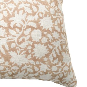 May include: A beige throw pillow with a white floral pattern. The pillow is made of a soft, textured fabric.