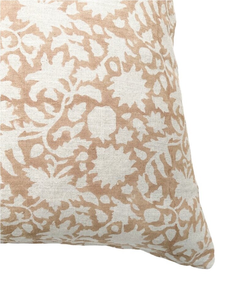May include: A beige throw pillow with a white floral pattern. The pillow is made of a soft, textured fabric.