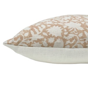 May include: A beige throw pillow with a white floral pattern. The pillow has a white border.