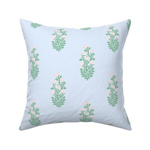 May include: A light blue square pillow with a repeating pattern of pink and green floral designs.