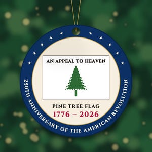 May include: A round, flat ornament featuring a central white rectangle with a green pine tree graphic and the text AN APPEAL TO HEAVEN. Below is PINE TREE FLAG and 1776-2026. The blue border displays 250TH ANNIVERSARY OF THE AMERICAN REVOLUTION.