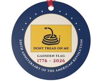Puede incluir: Un adorno redondo azul con una cinta roja que presenta la bandera de Gadsden, una serpiente enroscada y el texto DONT TREAD ON ME. Debajo dice GADSDEN FLAG 1776 - 2026 y 250TH ANNIVERSARY OF THE AMERICAN REVOLUTION, rodeado de estrellas blancas.