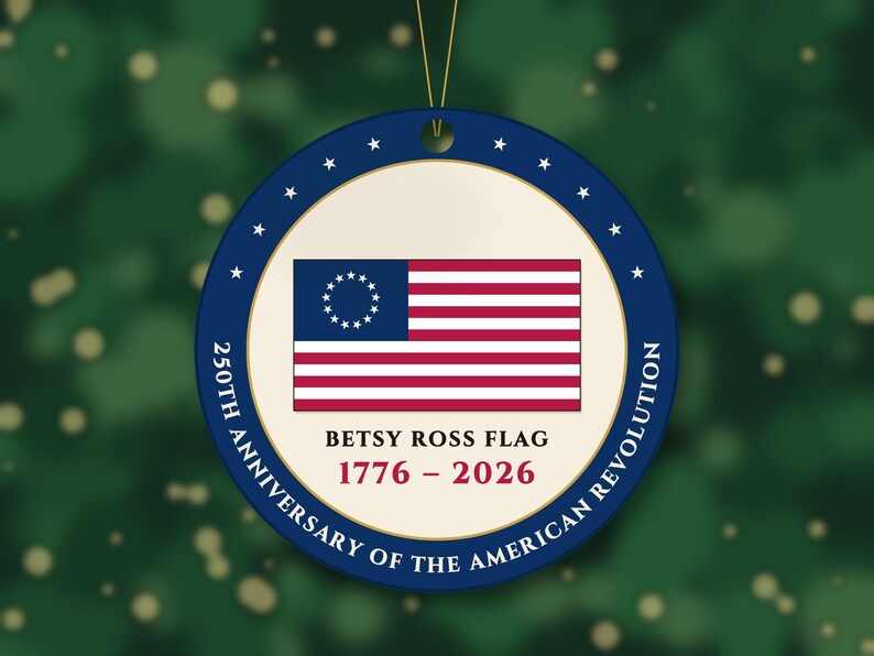 May include: A round, flat ornament featuring the Betsy Ross flag in the center. The text reads: BETSY ROSS FLAG 1776 - 2026 250TH ANNIVERSARY OF THE AMERICAN REVOLUTION. The border is dark blue with white stars and a gold inner ring.
