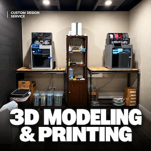 Könnte beinhalten: Ein Arbeitsbereich mit zwei 3D-Druckern auf Metallregalen und einem zentralen Holzschrank. Der Text lautet CUSTOM DESIGN SERVICE und 3D MODELING & PRINTING. Das Setup umfasst durchsichtige Aufbewahrungsboxen, Kartons und Filamentrollen.