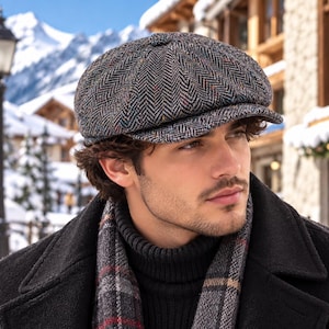 May include: A grey newsboy cap featuring a multi-colored herringbone pattern with subtle flecks of blue, orange, and white. The cap has a rounded, multi-paneled crown with a button at the top and a short, stiff brim extending over the forehead.