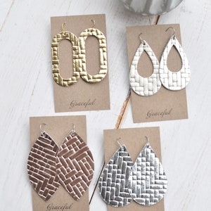 May include: Four pairs of leather earrings on display cards. The earrings are in gold, silver, and brown. The cards have the word "Graceful" printed on them.
