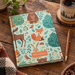 May include: A hardcover journal with a light green cover featuring a repeating pattern of forest animals including a fox, bear, deer, and rabbit, along with mushrooms and foliage. The word Adventures is printed in a rectangular orange box.
