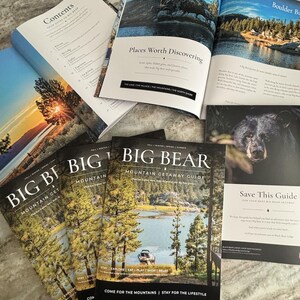 以下が含まれることがあります： 湖と森が表紙のBig Bear Mountain Getaway Guideマガジン数冊と、目次やPlaces Worth Discoveringと題された岩場の写真が掲載された見開きページが写っています。
