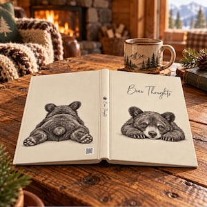 May include: A hardcover book titled Bear Thoughts with a cream-colored cover featuring a black and white sketch of a bear cub from behind on the left and a bear cub resting its head on its paws on the right, with a small QR code at the bottom.