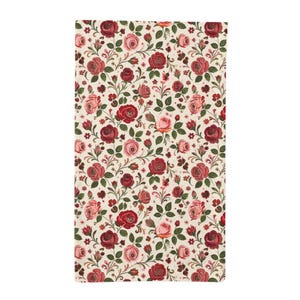 May include: A rectangular fabric textile featuring a repeating floral pattern of deep red and soft pink roses with green leaves and stems on a cream-colored background. The design includes various rose blooms and small buds arranged in a dense layout.