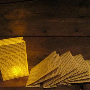 May include: A yellow paper bag lantern with text printed on it, lit from the inside. The text reads "treating all subjects in a similar tone of a walk but nowhere extraordinarily pretty, I have never been so much impressed. That this extraordinary..."
