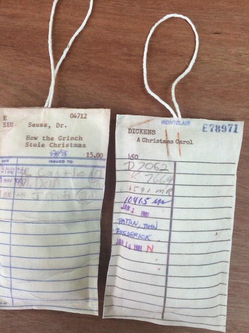 May include: Two vintage library checkout cards, one for "How the Grinch Stole Christmas" by Dr. Seuss and the other for "A Christmas Carol" by Dickens. Both cards have handwritten check-out information and dates.