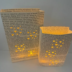 May include: Two paper lanterns with a yellow glow, made from book pages, with the text "The Punnett family had lived on for many years, yet retained an essentially English character." and "...the gru-gru stick about half of those vanished and truly forgotten men, the original Carib Indians. Among the several stone ..."