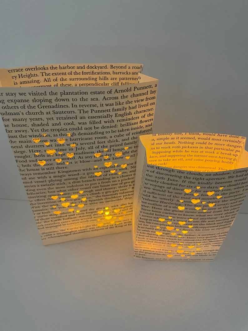 May include: Two book-shaped candle holders with a warm glow emanating from the pages. The candles are surrounded by small, twinkling lights, creating a magical and festive atmosphere. The text on the pages is visible, but the words are blurry.
