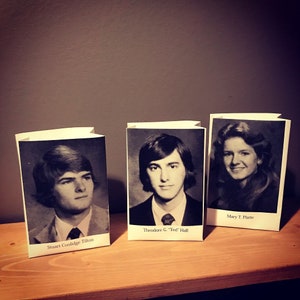 Op de afbeelding: Drie witte papieren zakken met zwart-witfoto's van mensen en hun namen eronder gedrukt. De namen zijn "Stuart Coolidge Tilton", "Theodore G. "Ted" Hall" en "Mary T. Platte".