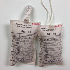 May include: Two white fabric tags with a red string attached. The tags are labeled "The Polar Express" and have a date of "84 19". The tags have a list of dates and signatures.