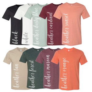 May include: Ten t-shirts in a variety of colours, including black, white, dusty blue, cardinal, sunset, tan, forest, maroon, and orange. Each shirt has a different colour and a white text label on the side that says "heather" followed by the colour name.