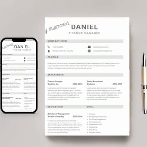 以下が含まれることがあります： Daniel Finance Managerというタイトルの履歴書テンプレート、同じ履歴書を表示したスマートフォン、シルバーとクリーム色のボールペン。この文書には、連絡先情報、プロフィール、職歴、学歴、スキルのセクションが含まれています。