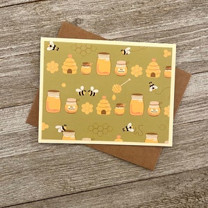 Puede incluir: Una tarjeta verde con un patr&oacute;n de tarros de miel, panales y abejas. El texto en los tarros dice "My Honey".